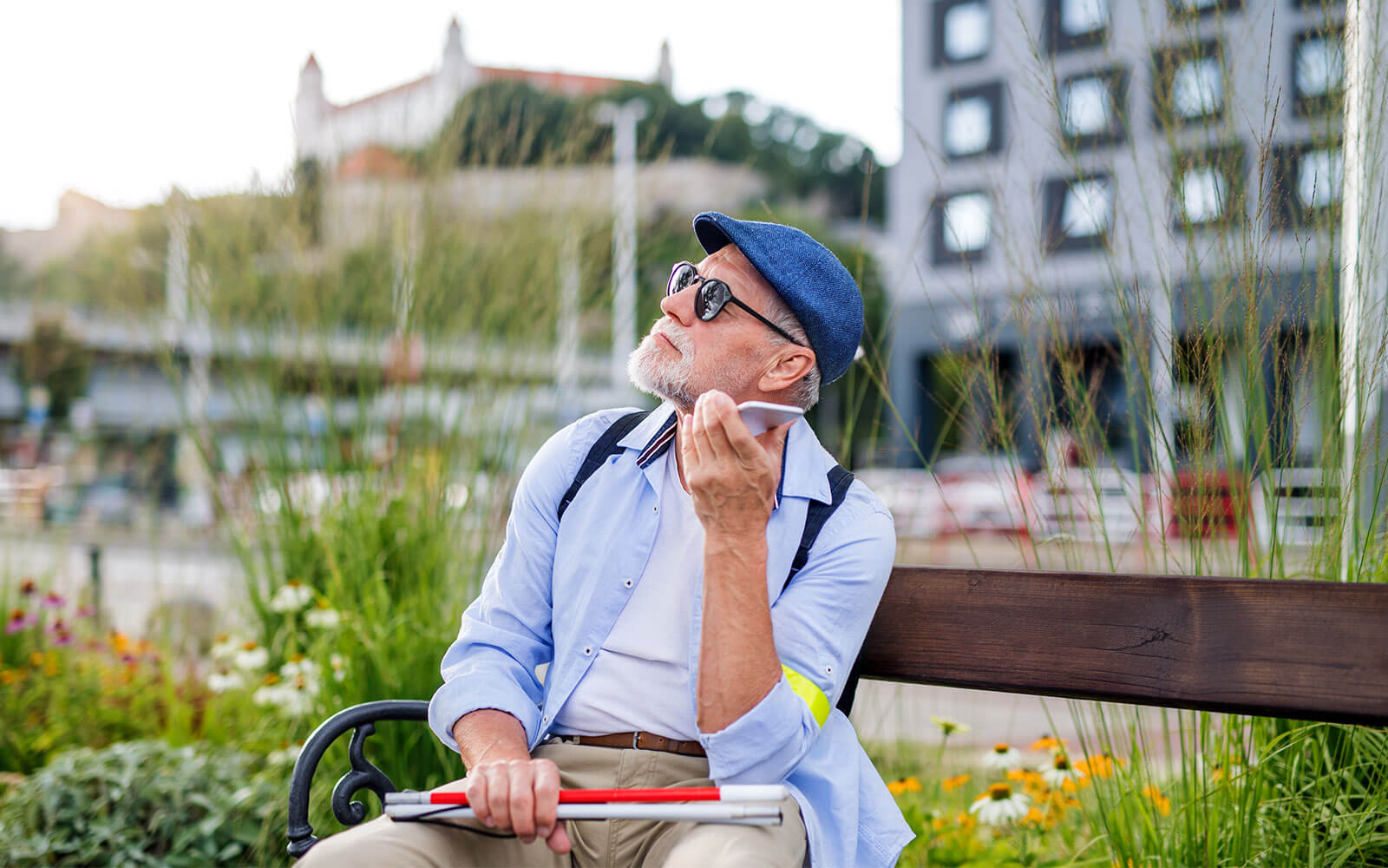 Sight impaired man sitting on a bench listening whilst on his phone