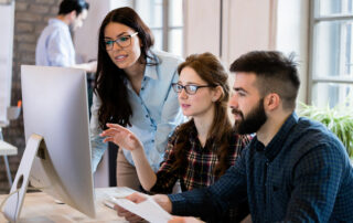 Team of three discussing something on computer