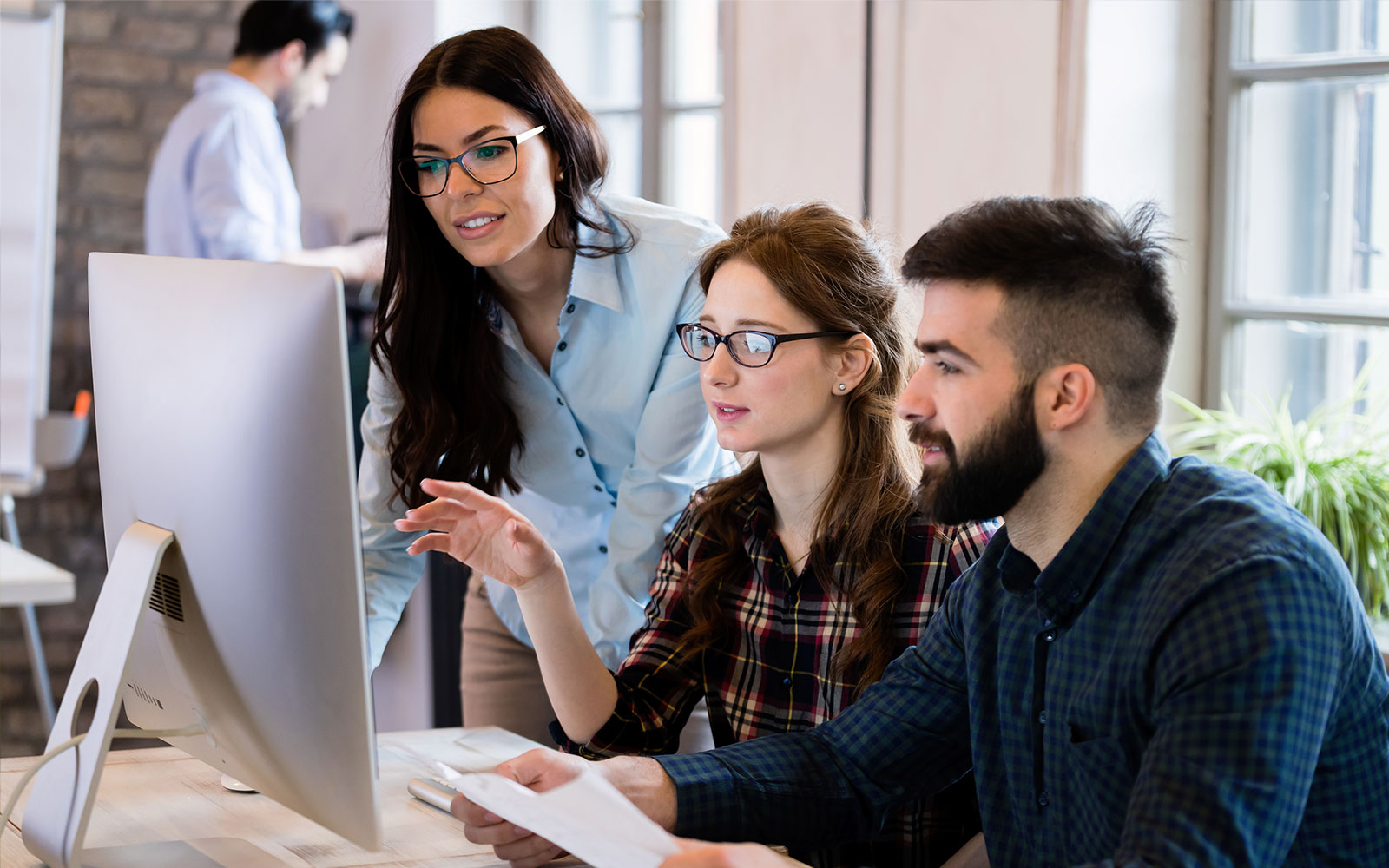 Team of three discussing something on computer