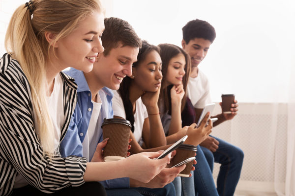 Friends using phones, texting and drinking takeaway coffee Friends using phones, texting and drinking takeaway coffee