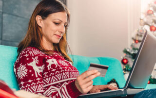 Woman in festive jumper shopping online with credit card