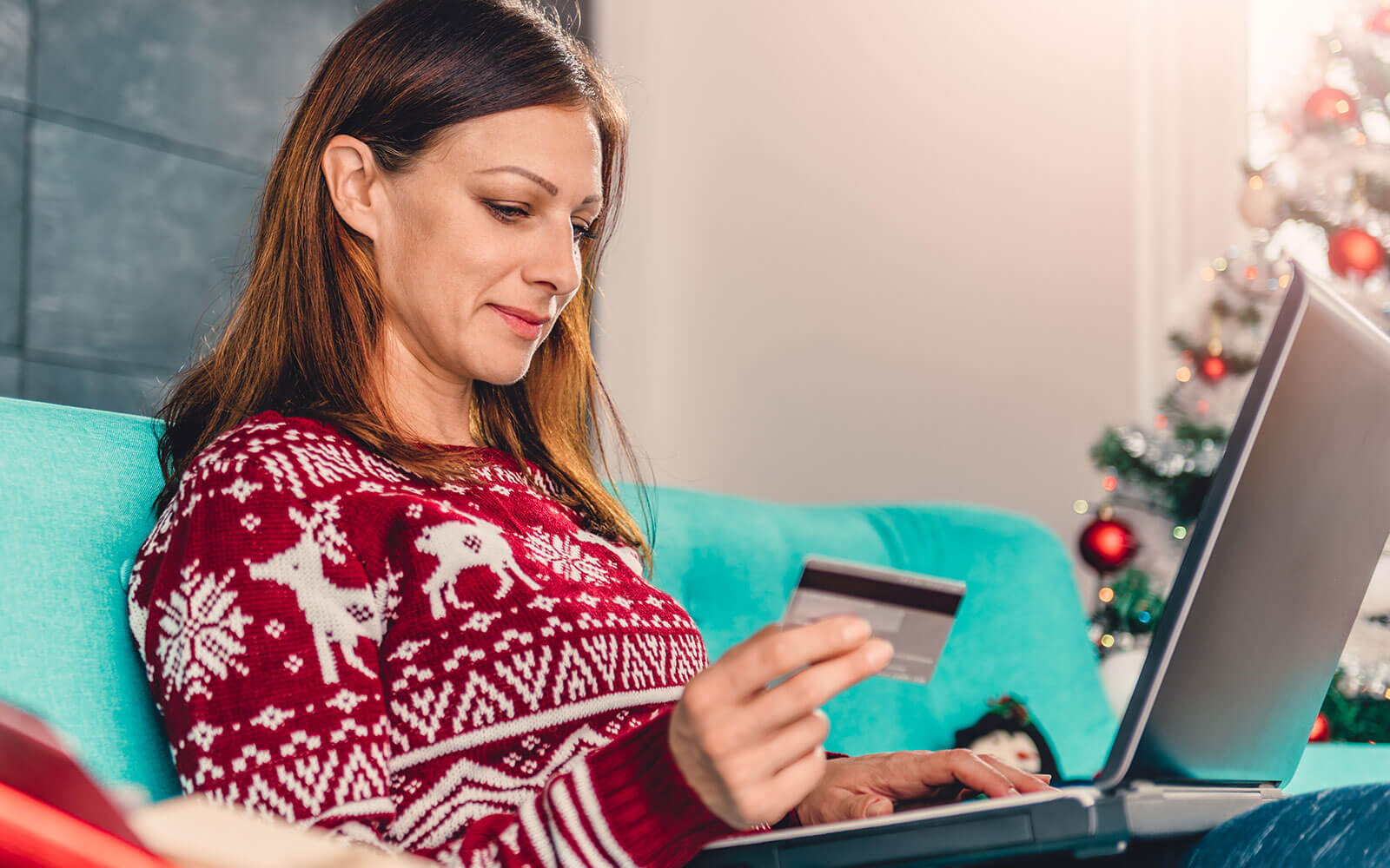 Woman in festive jumper shopping online with credit card