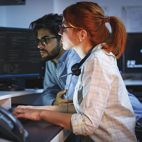 Woman and man staring intently at computer screen