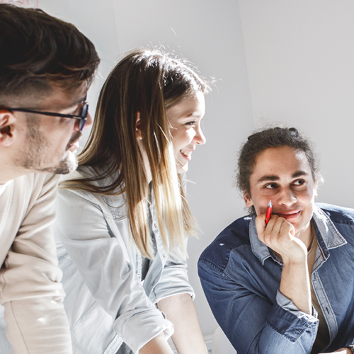 Three coworkers smiling and looking at colleague