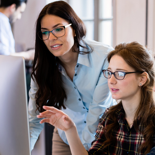 Young woman shows her colleague a report on a computer screen