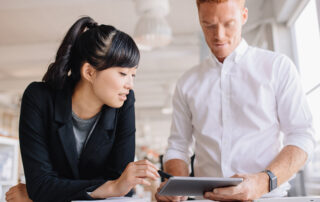 man and woman discussing work looking at tablet