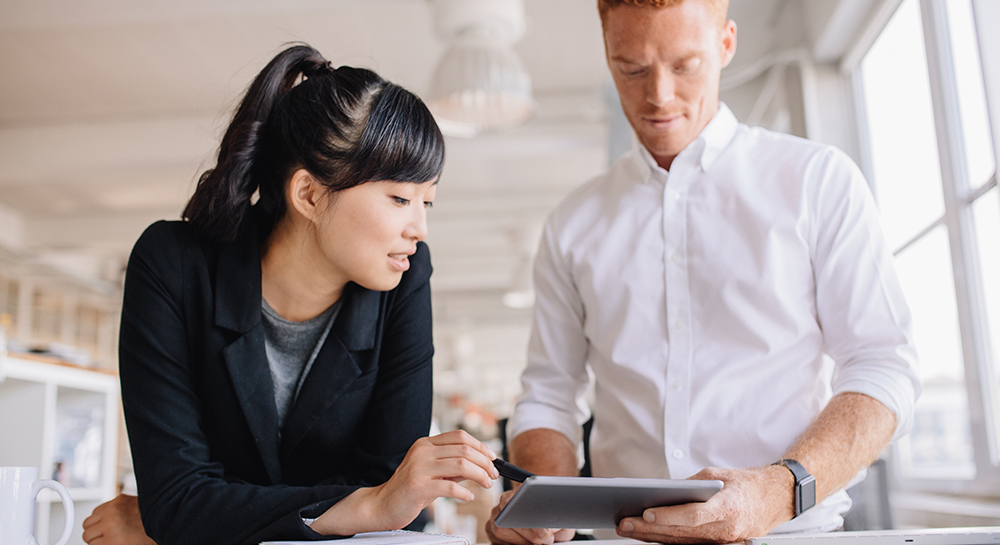 man and woman discussing work looking at tablet