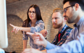 Woman pointing at screen in company of two colleagues