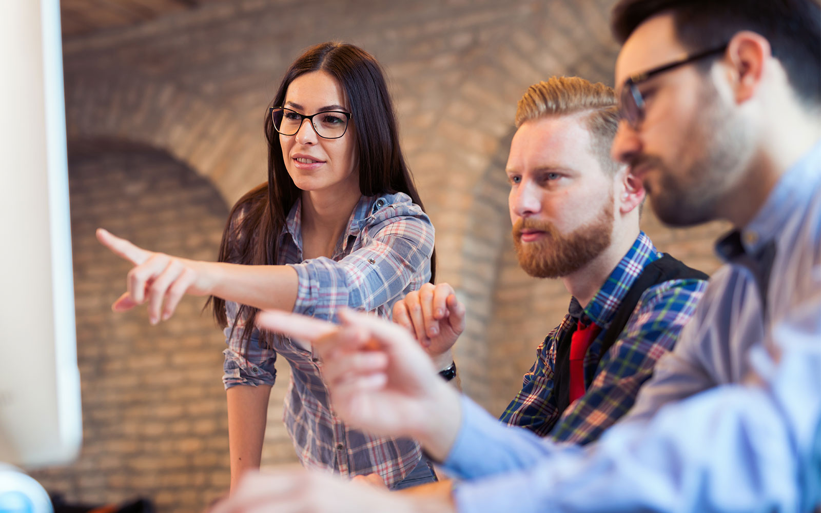 Woman pointing at screen in company of two colleagues