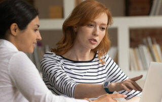 Woman discussing something on laptop screen with colleague