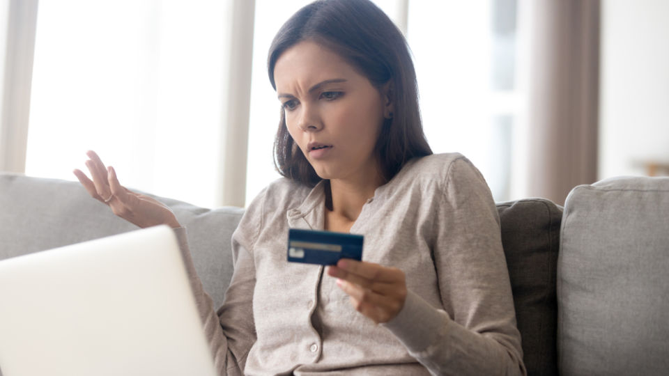 Woman using laptop frustrated and holding payment card
